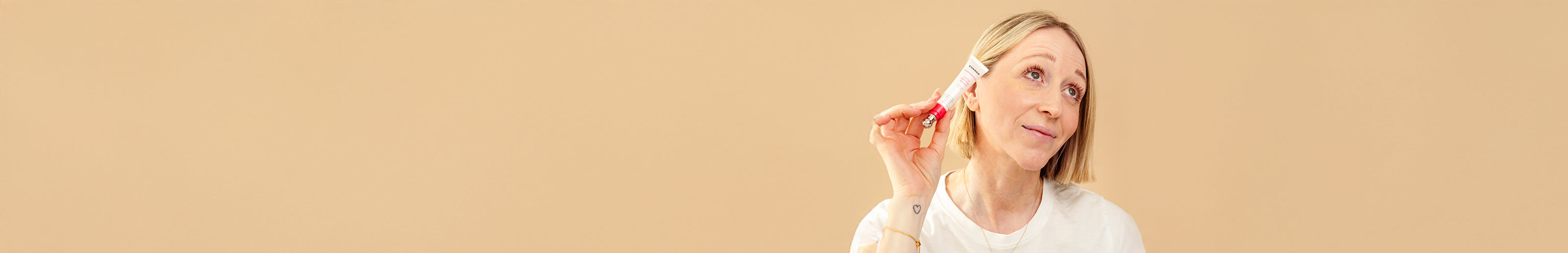 Woman holding a small white box with a red ribbon against a beige background