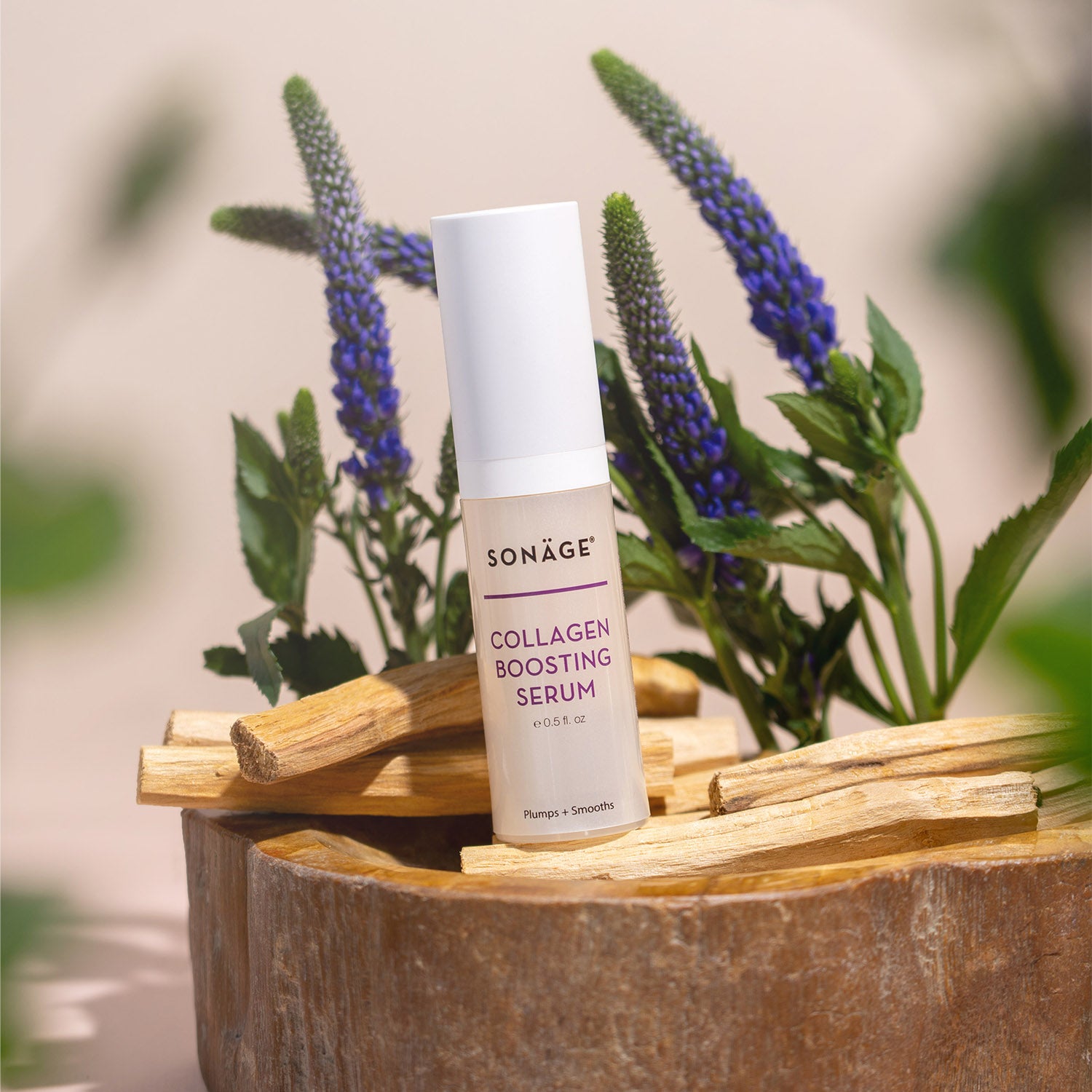 Collagen Boosting Serum in front of purple flowers