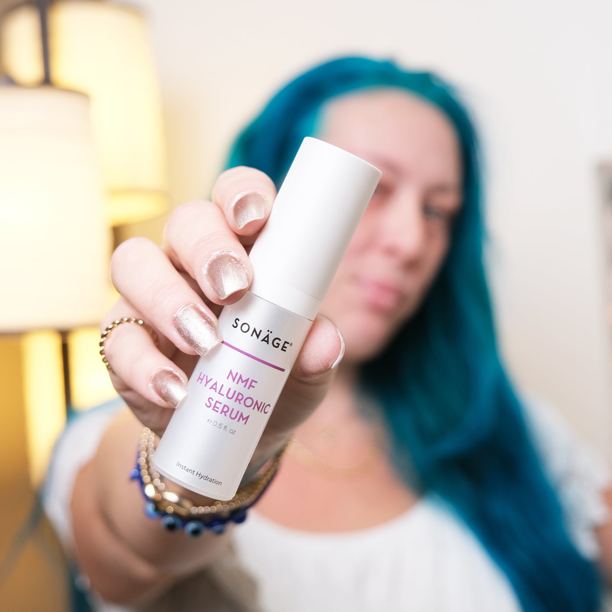 Woman with blue hair holding NMF Hyaluronic Serum
