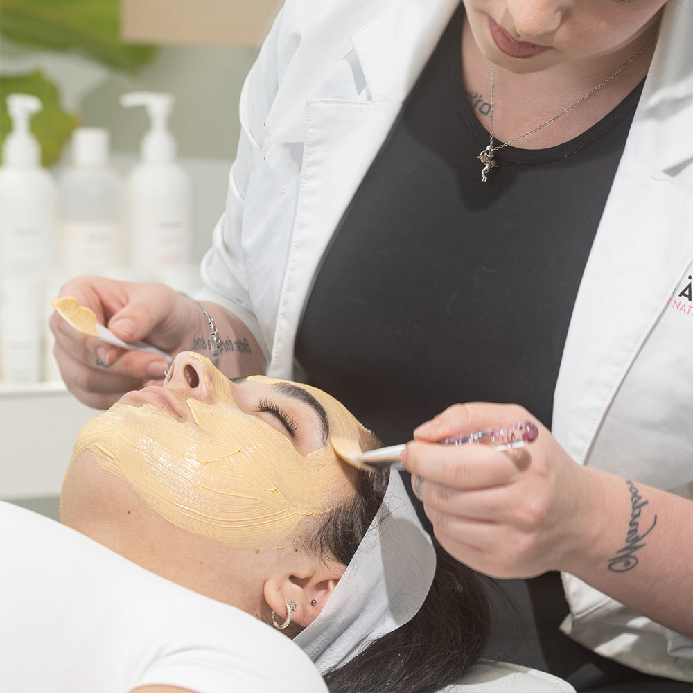 Person receiving a facial treatment with a skincare professional applying a mask.