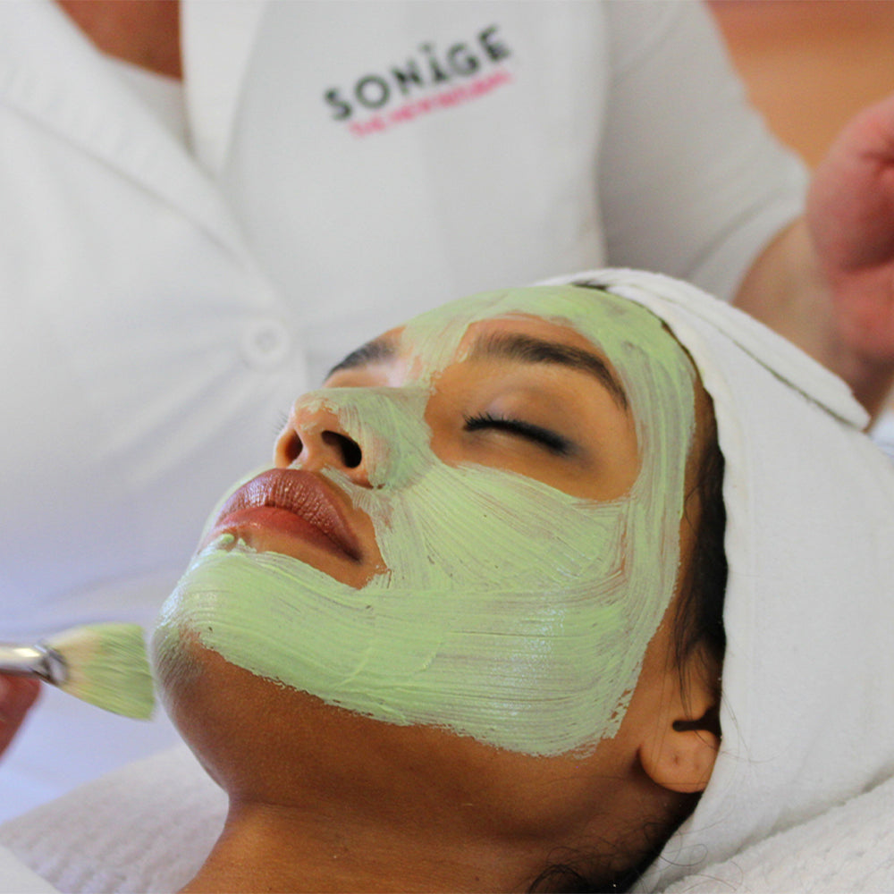 Person receiving a facial treatment with a green mask, SONAGE branded background