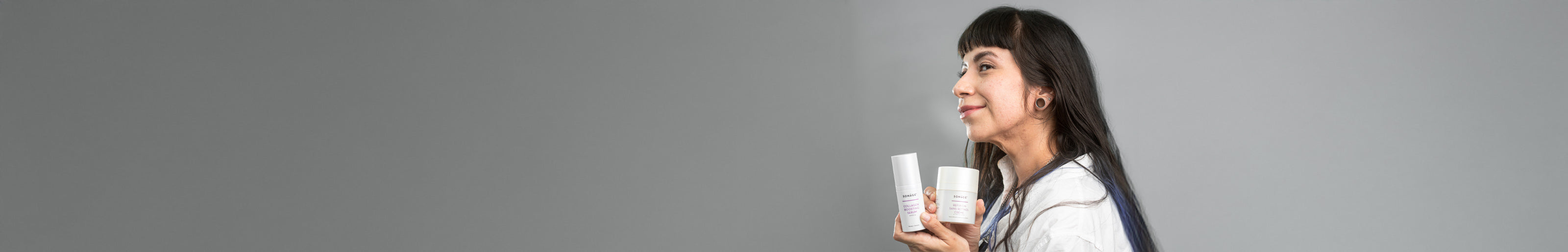 Woman holding two small containers against a gray background