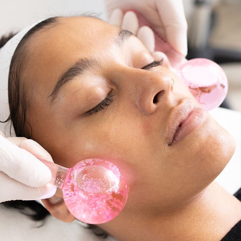 Person receiving a facial treatment with pink gel pads on a blurred background