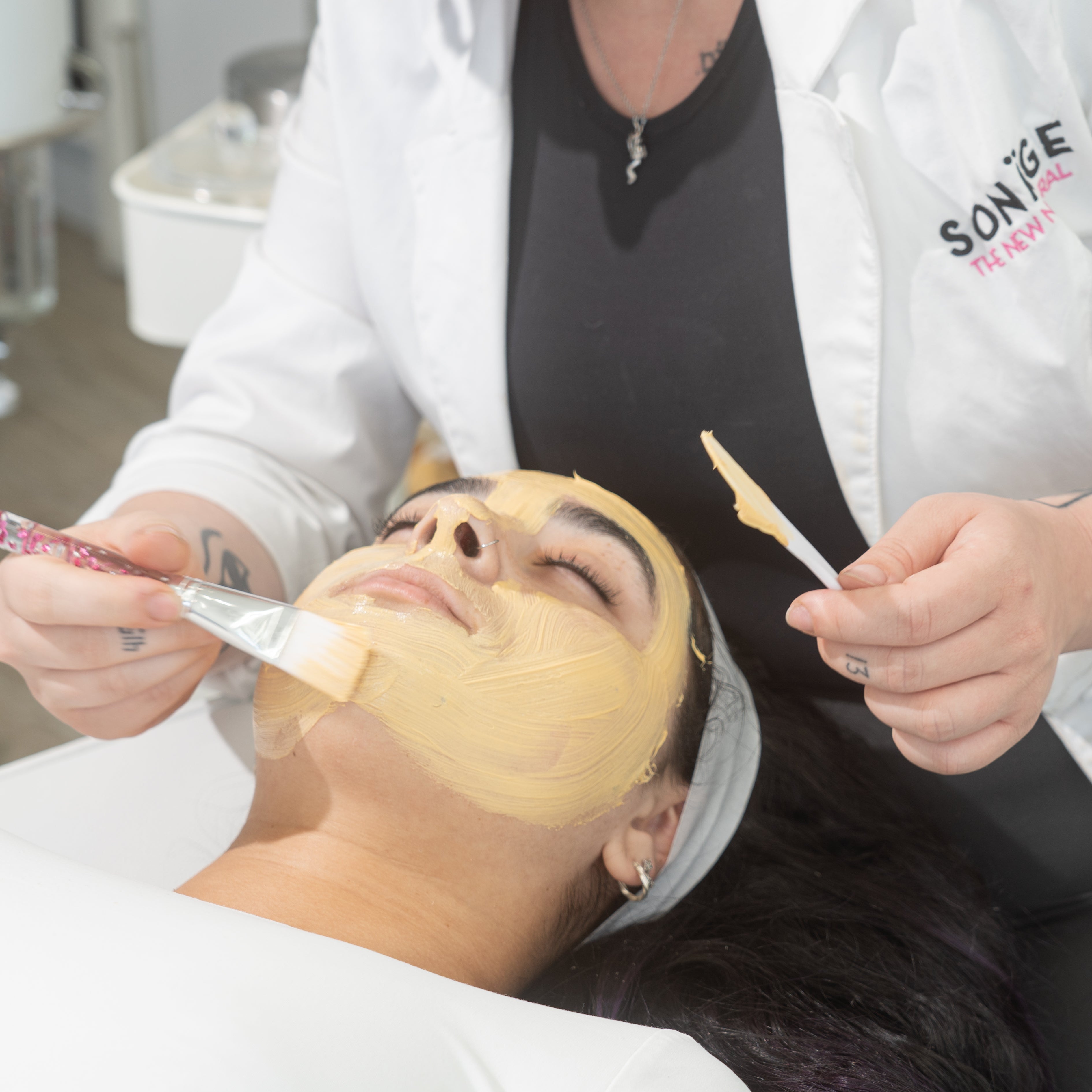 Person receiving a facial treatment with a skincare professional at a salon.