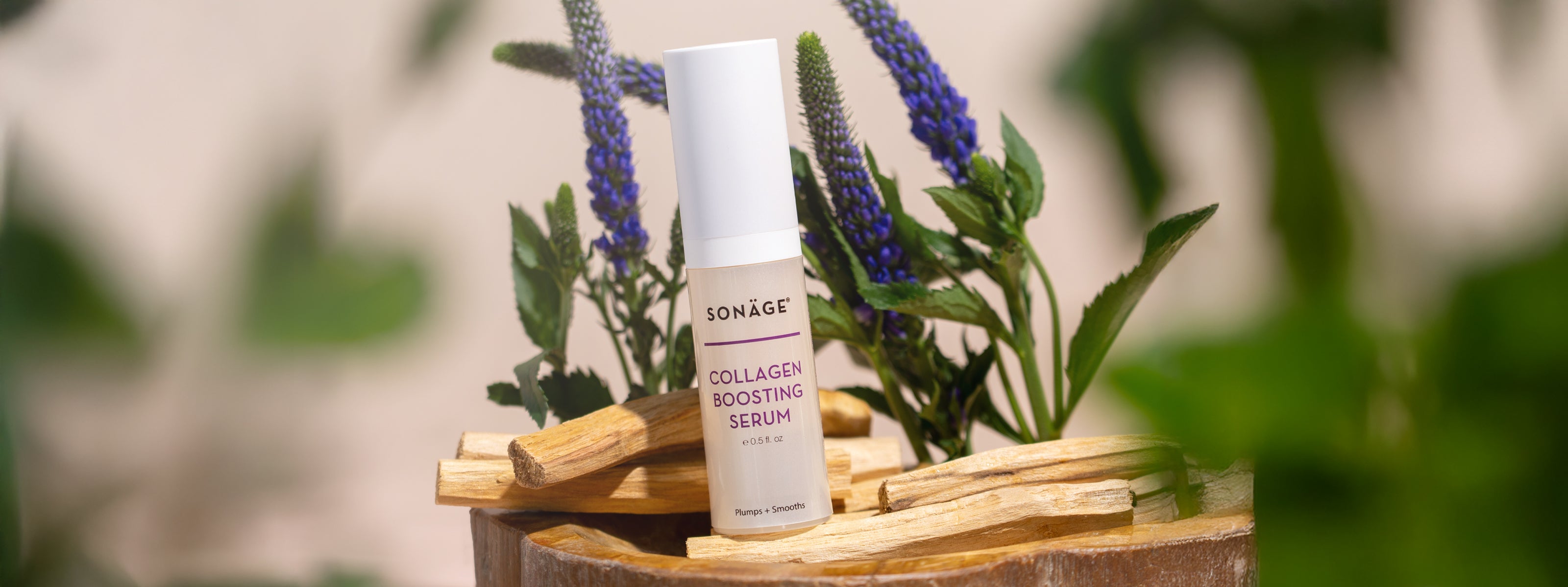Collagen Boosting Serum in front of purple flowers